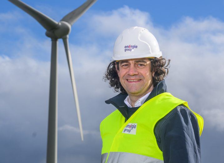 David Macartney of Energia Group, wearing a hard hat and a high visibility vest with a wind turbine in the background.