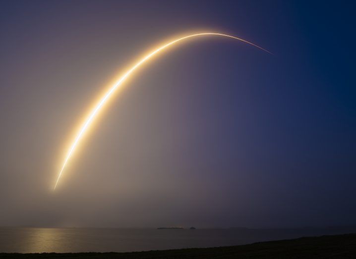 Photo of what appears to be the launch of a Falcon 9 rocket hurtling towards space and leaving behind a glowing trail.