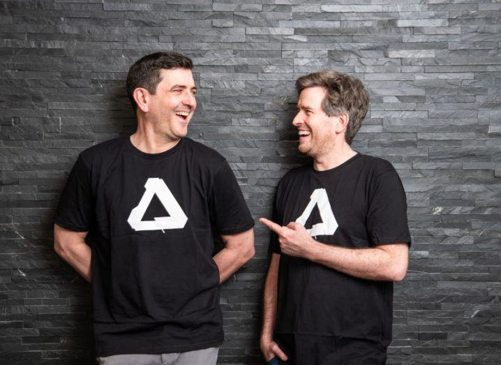 Two men from Canva and Affinity, speaking to each other in front of a grey wall.