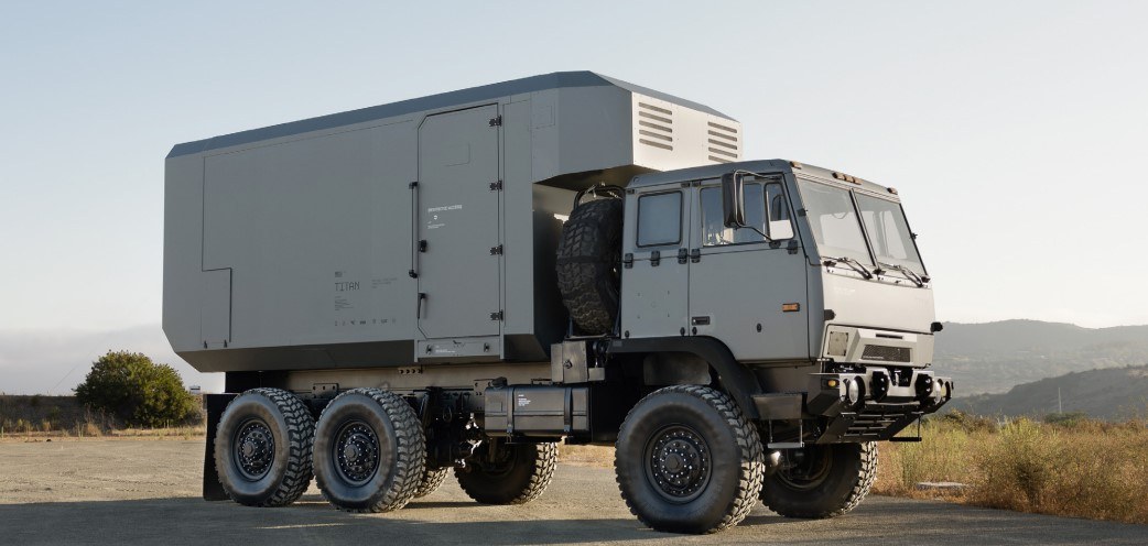 A grey military truck on a road. The truck is a Titan prototype.