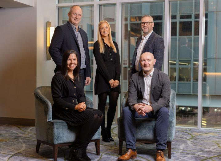 Three men and two women from Whiterock standing and sitting together in a group in a room. These individuals are managing a Whiterock growth fund for companies in Northern Ireland.