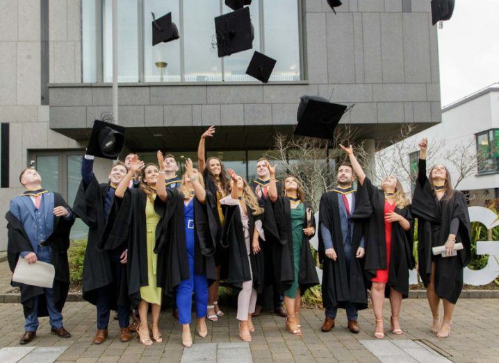 A group of university students throwing their graduation hats into the air.
