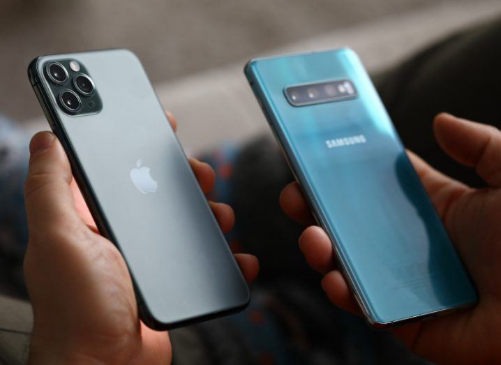An Apple smartphone and a Samsung smartphone, both held in a person's hands.