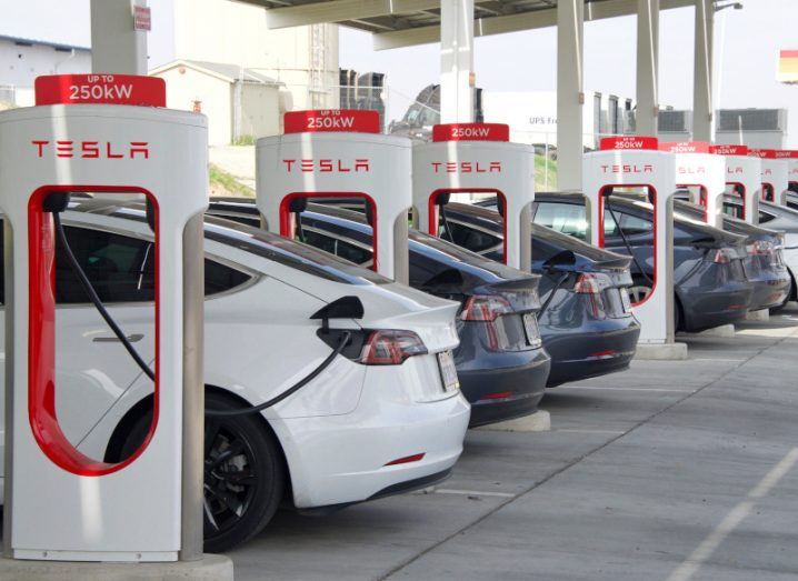 Multiple vehicles next to Tesla EV charging stations.