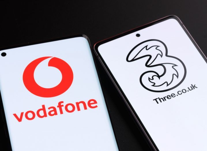 Two smartphones with the Vodafone and Three logos on the screens.
