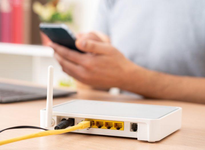 A router on a table with a person sitting behind it. Used for the concept of smart devices.