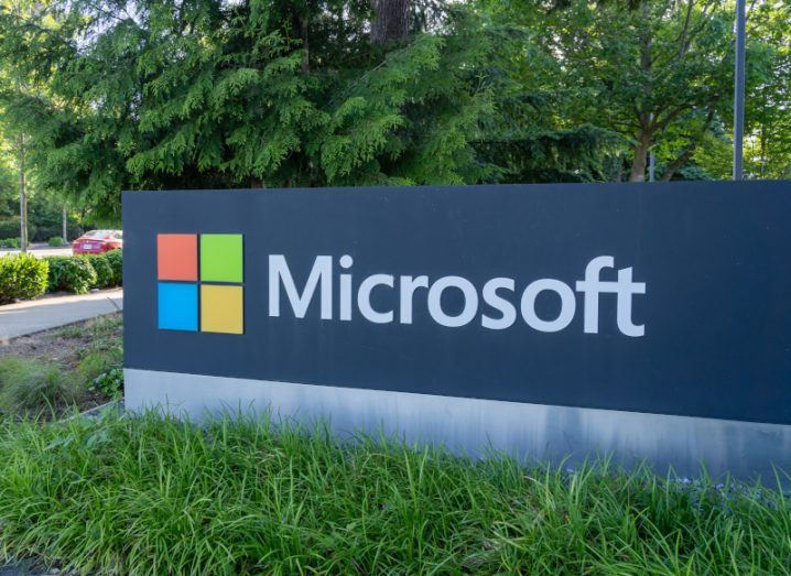The Microsoft logo on a sign on a patch of grass.