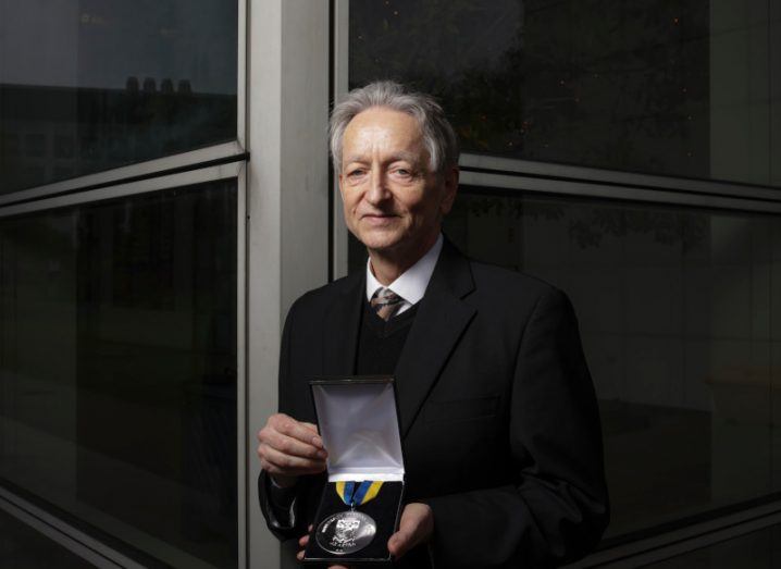 A photo of Geoffrey Hinton holding a UCD award in his hands.