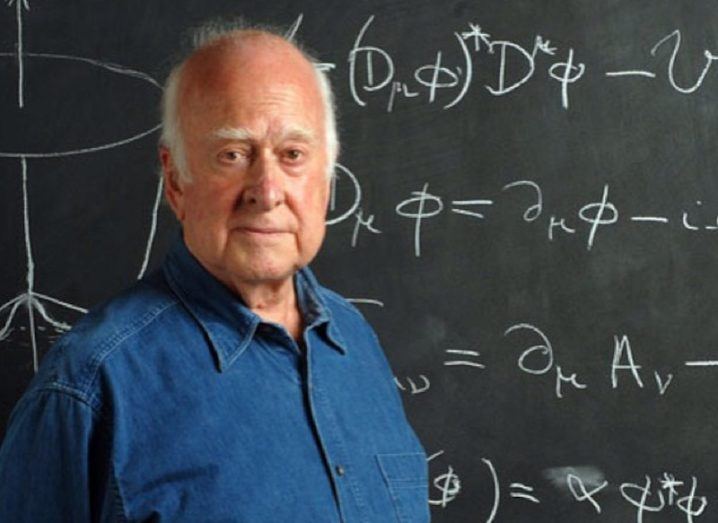 Prof Peter Higgs standing in front of a chalkboard.