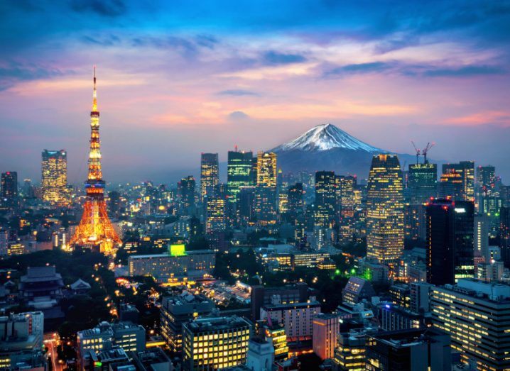 Skyline of Tokyo in what appears to be the evening with Mount Fuji visible in the background.