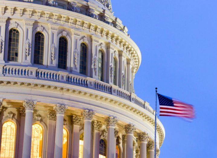 The US capitol building with an the country's flag next to it.