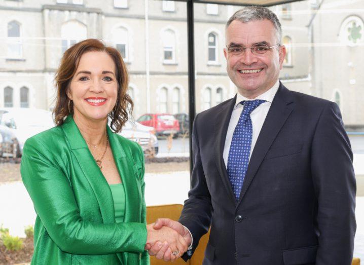 Crew Digital CEO Niamh Costello and Dara Calleary, TD stand next to each other and shake hands while smiling at the camera.