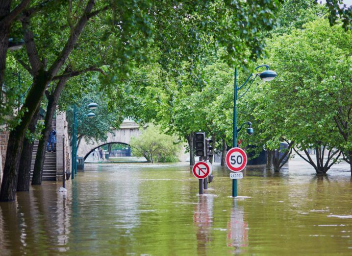 A flooded street in Paris with tops of street signs and trees visible above brown flood waters.