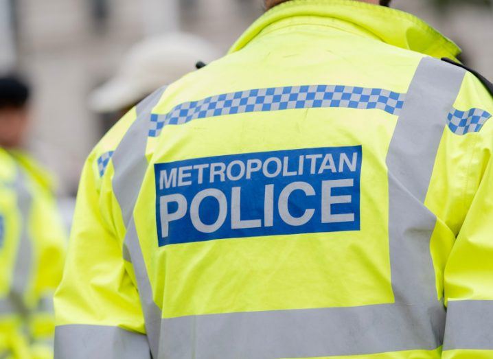 A close-up of the Metropolitan police logo on the back of a police officer's high vis jacket.