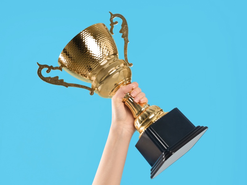An arm lifts a trophy to signify winning first place in an awards event.