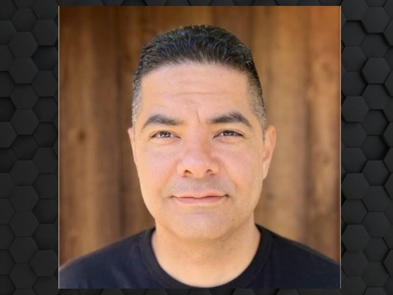 A man wearing a black shirt smiles in front of a wooden wall. He is Alan Talanoa, the chief technology officer at Aircall.