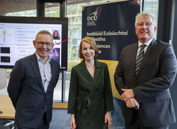 Two men and a woman from DCU standing together in a room.