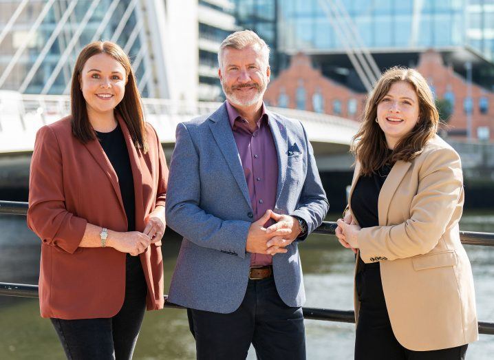 Two women and a man, all executives at Expleo, standing outdoors near the Liffey.